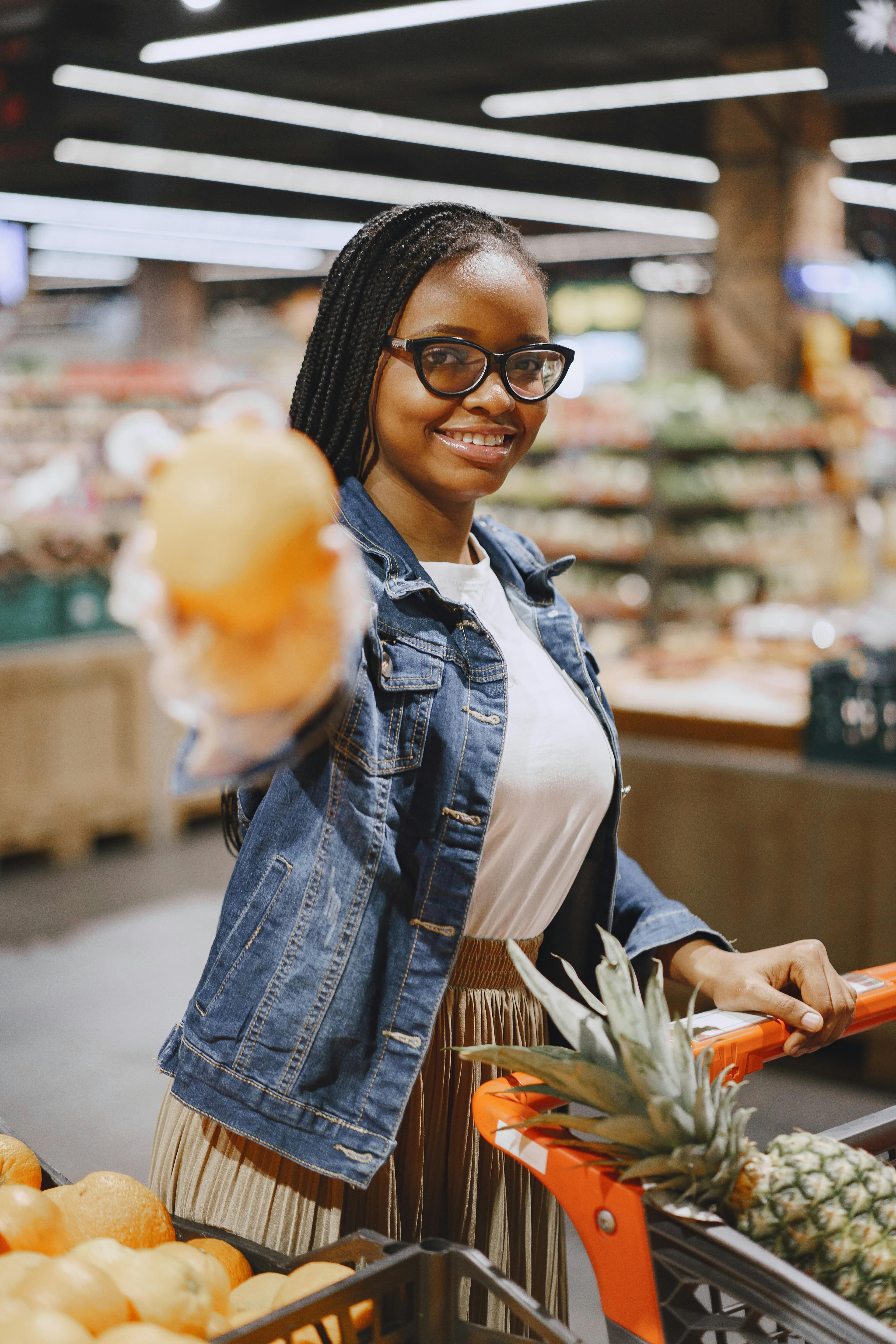 A woman in a denim jacket shopping for groceries in a supermarket.