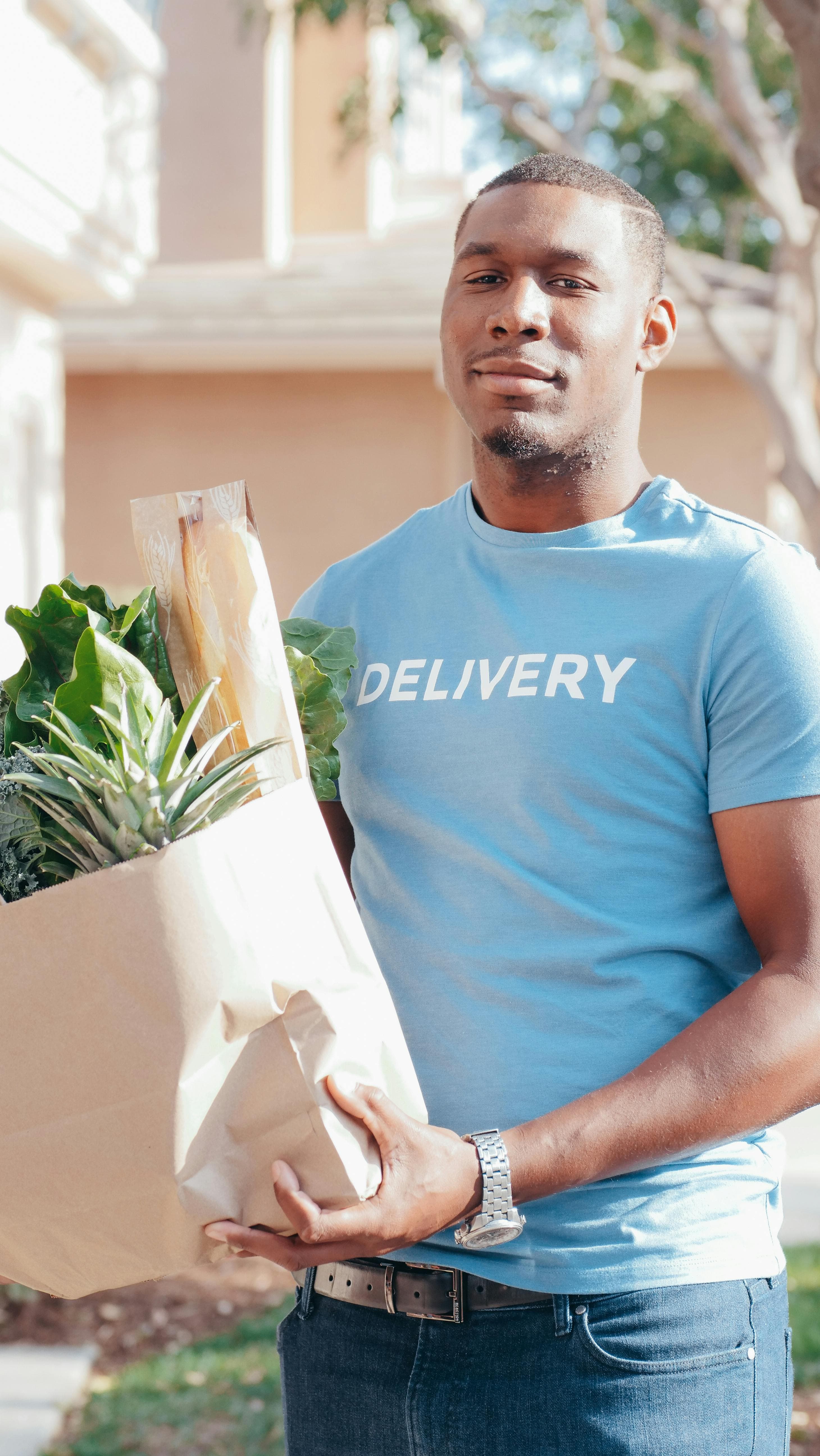 A man holding a paper bag of fresh groceries.